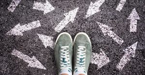 sneaker shoes and arrows pointing in different directions on asphalt ground, choice concept